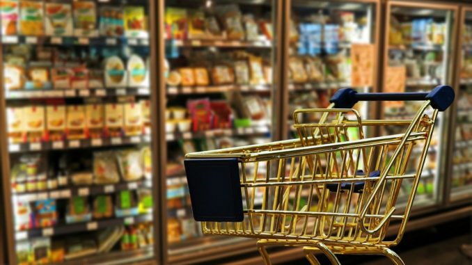 Interno di un supermercato con un carrello della spesa vuoto davanti agli scaffali