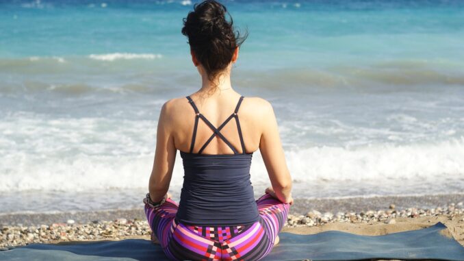 Una meditatrice su una spiaggia di fronte al mare