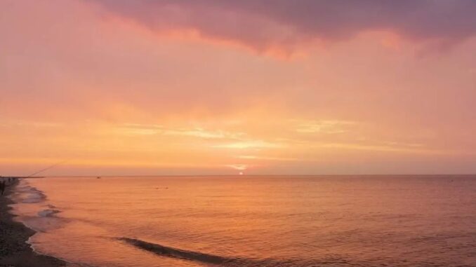 Una rossa alba ad Albenga sulla spiaggia con vista mare e orizzonte nella foto di Roberto Ruaro