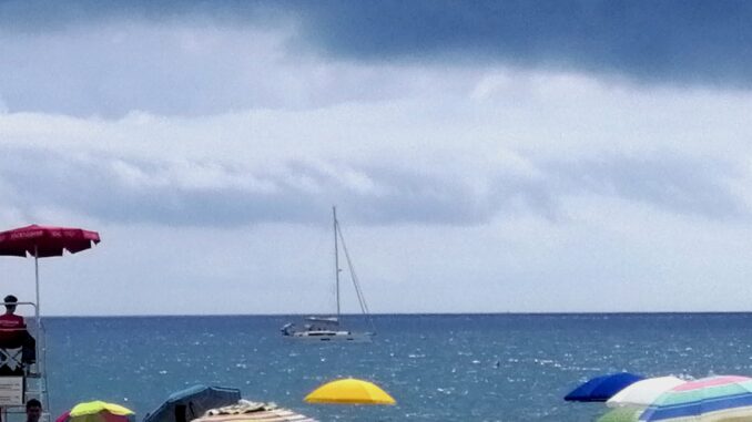 Albenga con vista mare e una barca a vela che si allontana dalla spiaggia nella foto di Roberto Ruaro