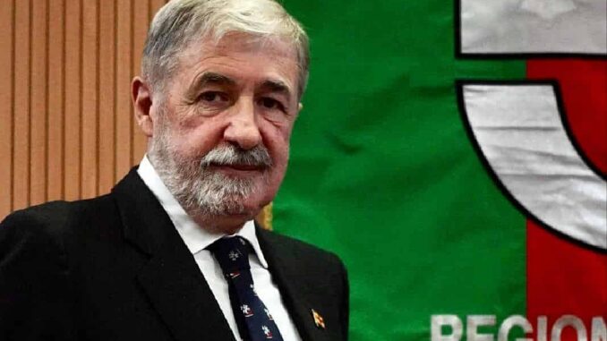 il presidente Marco Bucci vicino allo stendardo istituzionale della Regione Liguria