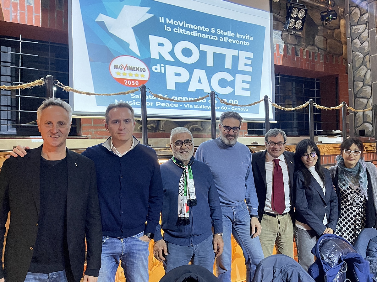 Un gruppo a Genova di sette persone posa per una foto davanti a uno striscione con la scritta "Rotta di Pace" e "Movimento 5 Stelle". Nello striscione anche una colomba e informazioni sull'evento. Nel gruppo ci sono il capogruppo regionale M5S Stefano Giordano, l’europarlamentare Gaetano Pedullà, il senatore Luca Pirondini e il senatore Marco Croatti.