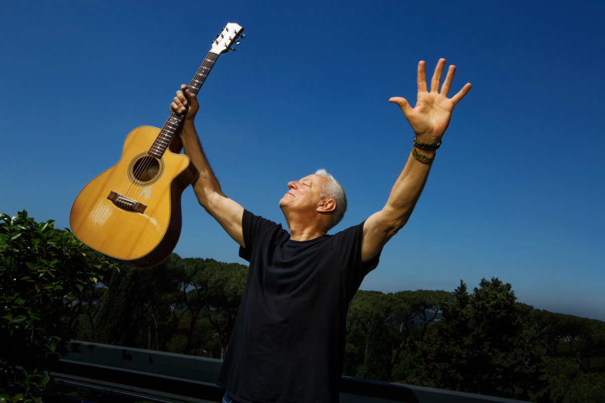 Nella foto Tommy Emmanuel alza la chitarra e le mani al cielo alla fine di una performance (Crediti: foto Luciano Viti)