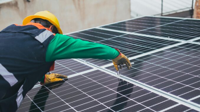 Un operaio lavora su un tetto con i pannelli fotovoltaici