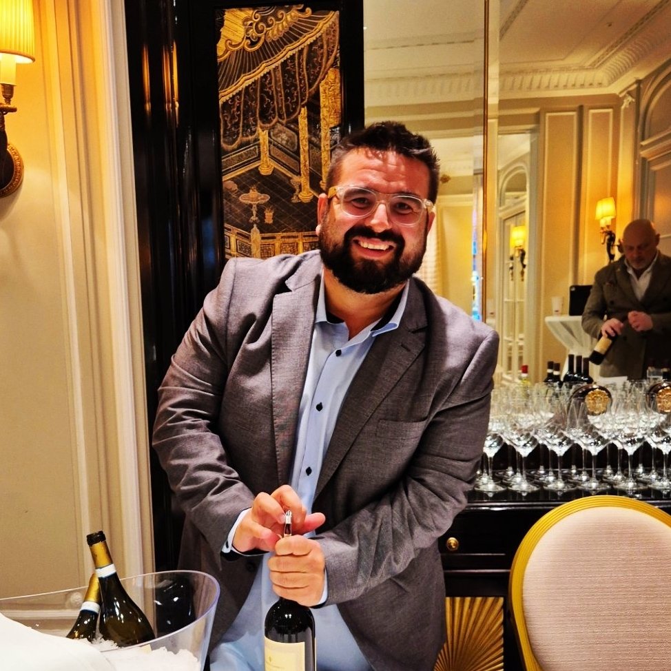 Jacopo Fanciulli sorridente stappa una bottiglia durante una degustazione di vino a Le Prime di Vite in Riviera