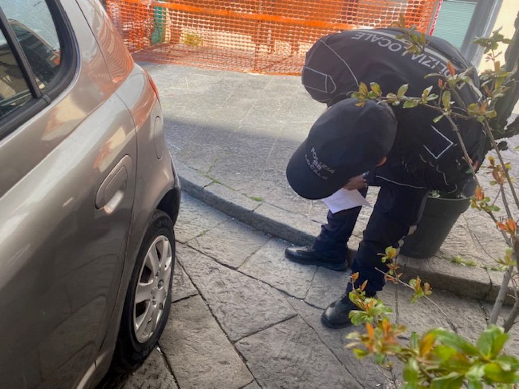 Polizia Locale Albenga indagini, agente ispezione veicolo e gomma tagliata