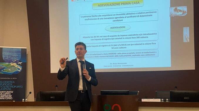 Mastroianni parla alla platea sulle agevolazioni prima casa; di9etro di luj sullo schermo grande della sala la slide tematica